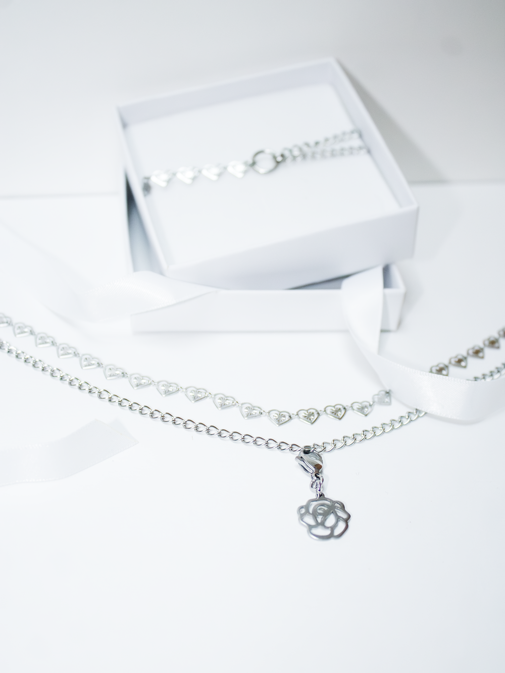 parure bijoux argenté avec un bracelet et un ras de cou en forme de coeur plus une pendentif rose